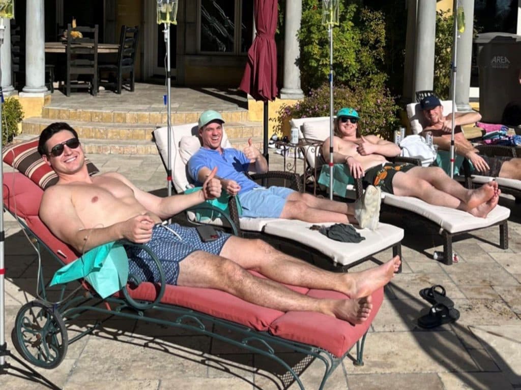 Clients receiving IV drips on poolside loungers during a group session