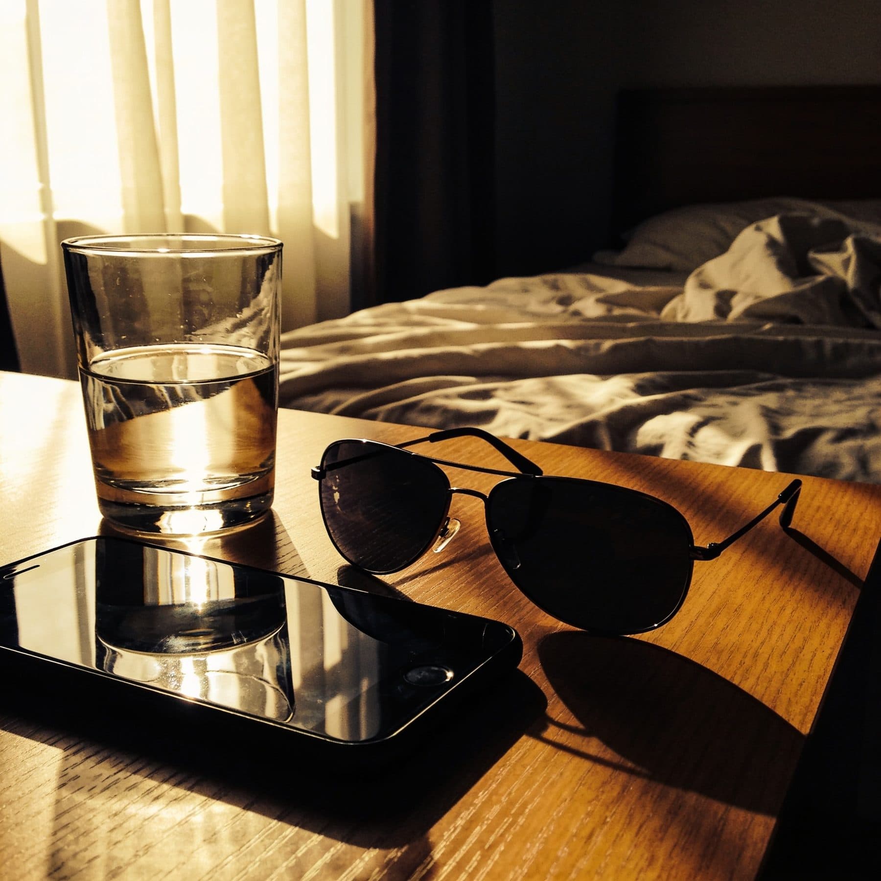 Morning-after bedside table with sunglasses and a glass of water