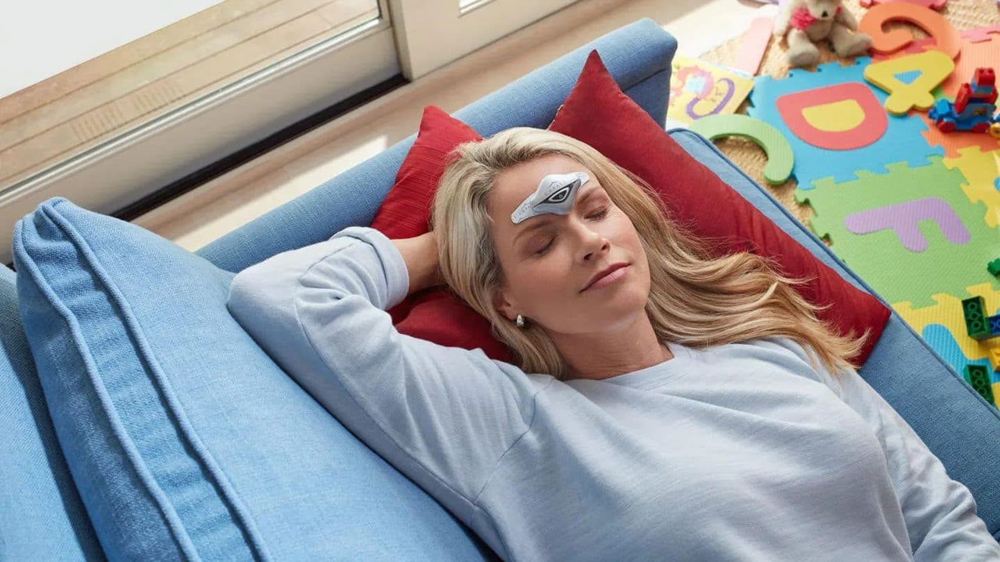 Woman resting on a couch with a cooling strip easing her headache